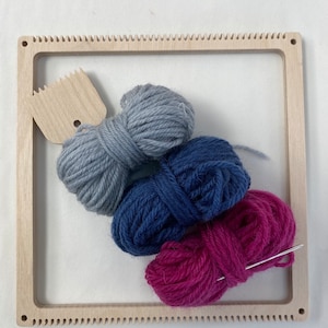 May include: A wooden loom with a gray, blue, and pink yarn balls and a needle.