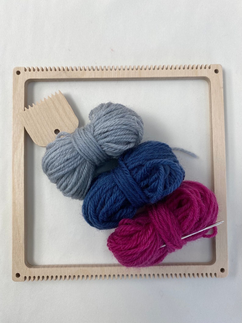 May include: A wooden loom with a gray, blue, and pink yarn balls and a needle.