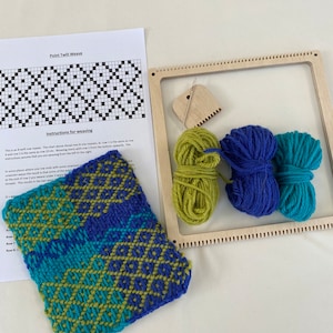 May include: A wooden loom with three balls of yarn: green, blue, and teal. The loom is set up for weaving and there is a partially woven piece of fabric in the foreground. The fabric is a point twill weave with a geometric pattern in green, blue, and teal.
