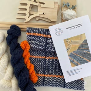 May include: A weaving kit with four shafts, a rigid heddle, yarn in white, orange, and navy blue, and instructions for a four-shaft sampler pattern. The kit includes a wooden loom, a rigid heddle, and yarn in white, orange, and navy blue. The instructions are for a four-shaft sampler pattern.
