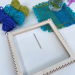 pinless pin loom with an example of a fabric square woven on the loom with balls of the wool used and tapestry needle.
