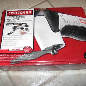 May include: A red and white box with the Craftsman logo and the text "12 Volt Compact Multi-Tool" on the front. The box contains a white and black multi-tool with a variety of attachments. The box also includes the text "NEXTEC 12 Volt Lithium Ion" and "#17438".
