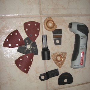 May include: A gray and black multi-tool with a variety of attachments, including sanding discs, a cutting blade, and a grinding wheel. The tool is labeled "Craftsman Nextec".