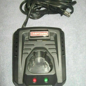 May include: Black Craftsman DieHard 12V battery charger with a green and red indicator light. The charger has a cord with a plug.
