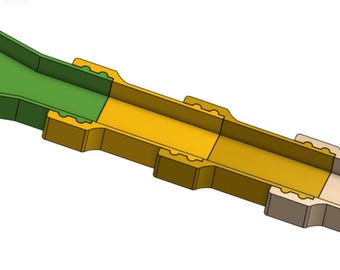 May include: A cross-section of a multi-colored, elongated object. The object is primarily yellow, with a green section on one end and a beige section on the other. The object has a rectangular shape with a hollow interior.