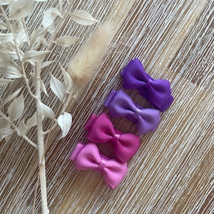 May include: Four ombre hair clips in shades of purple, pink, and lavender. The clips are arranged in a row from darkest to lightest.