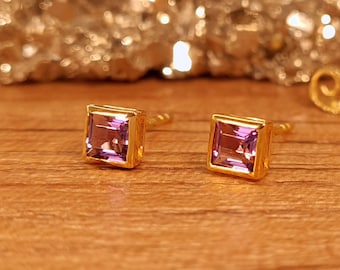 May include: A pair of gold stud earrings with square-shaped amethyst gemstones.