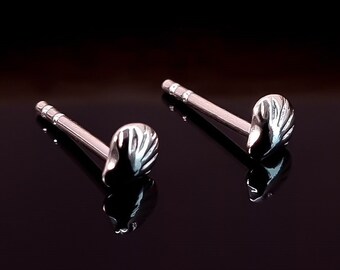 May include: A pair of silver shell stud earrings. The earrings are small and delicate, with a simple design.