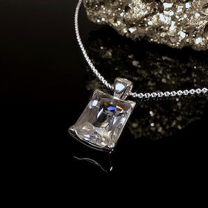 May include: A silver chain necklace with a clear, rectangular crystal pendant.