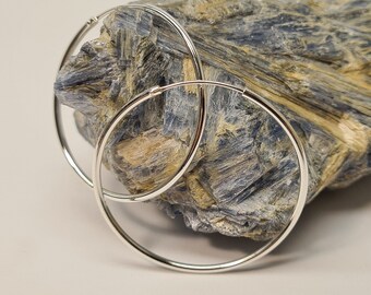 May include: A pair of silver hoop earrings. The earrings are round and have a smooth finish.