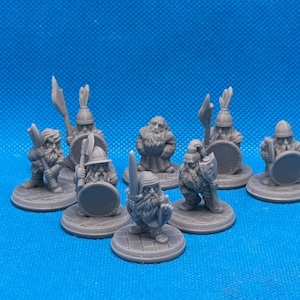 May include: A set of seven gray plastic miniature figurines of dwarves, each holding a weapon or shield, standing on round bases.