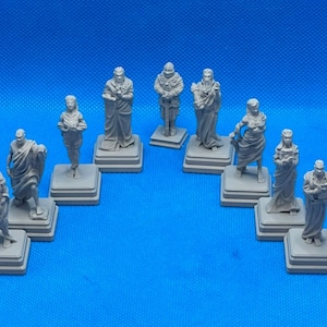 May include: Ten gray painted miniature statues of people in various poses, standing on square bases. The statues are arranged in a semi-circle on a blue surface.