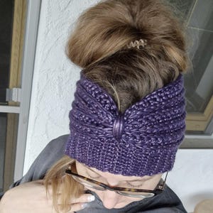 以下が含まれることがあります： 紫色のニットのヘッドバンドにリボンが付いている。ヘッドバンドは茶色の髪の女性が着用している。