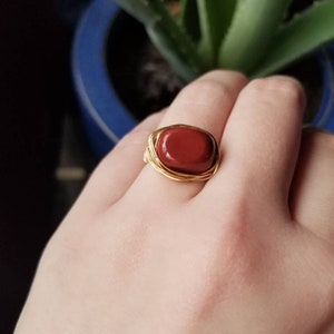 May include: A gold wire wrapped ring with a red gemstone.