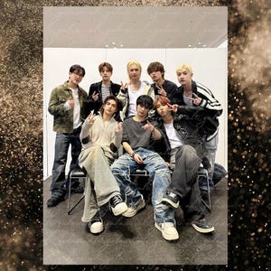 May include: Group of eight people posing for a photo. They are wearing a variety of casual outfits, including jackets, jeans, and t-shirts. The group is standing and sitting in front of a plain background. The image has a warm, slightly desaturated color palette.