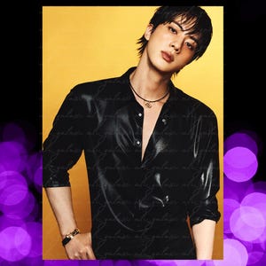 May include: A person with dark hair wearing a black button-down shirt with a subtle sheen, a thin black cord necklace with a gold-toned circular pendant, and a gold-toned link bracelet on their wrist, set against a solid yellow background.