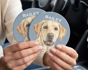 May include: Two round car cup holder coasters featuring a light blue background and a realistic illustration of a yellow Labrador retriever dog. The name BAILEY is printed in white capital letters above the dog's head on each coaster.