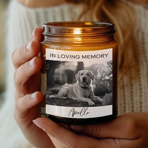 May include: A brown glass candle with a white label that says "In Loving Memory" and features a black and white photo of a dog named "Apollo".
