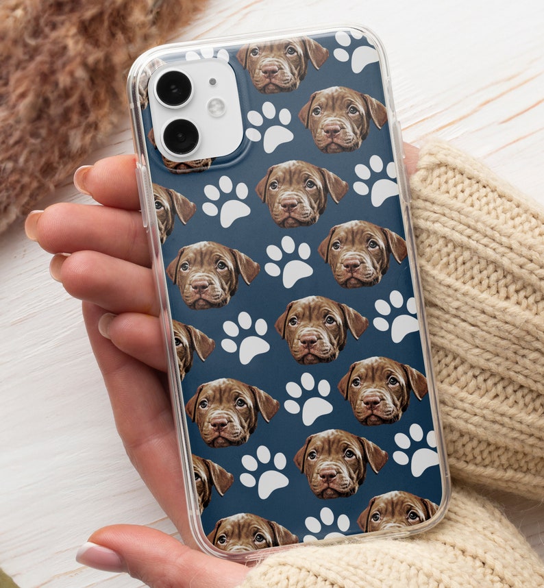 May include: A clear phone case with a blue background and a repeating pattern of white paw prints and brown dog faces.