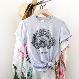 May include: Gray t-shirt with a black and white illustration of a dog's head and the name "Cooper" printed on the front.