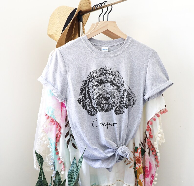 May include: Gray t-shirt with a black and white illustration of a dog's head and the name "Cooper" printed on the front.
