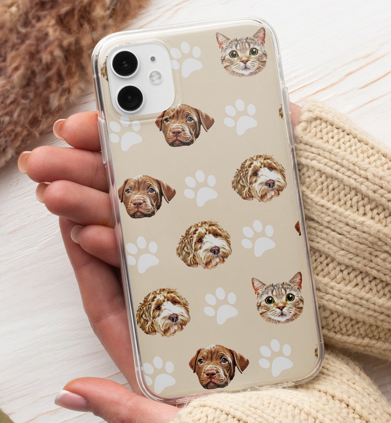 May include: A clear phone case with a tan background and white paw prints. The case features a repeating pattern of dog and cat faces.