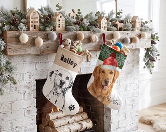 May include: Two personalized Christmas stockings hanging from a wooden mantel. The left stocking is cream-colored with a black ink drawing of a Dalmatian and the name Bailey. The right stocking features a golden retriever wearing a Santa hat.