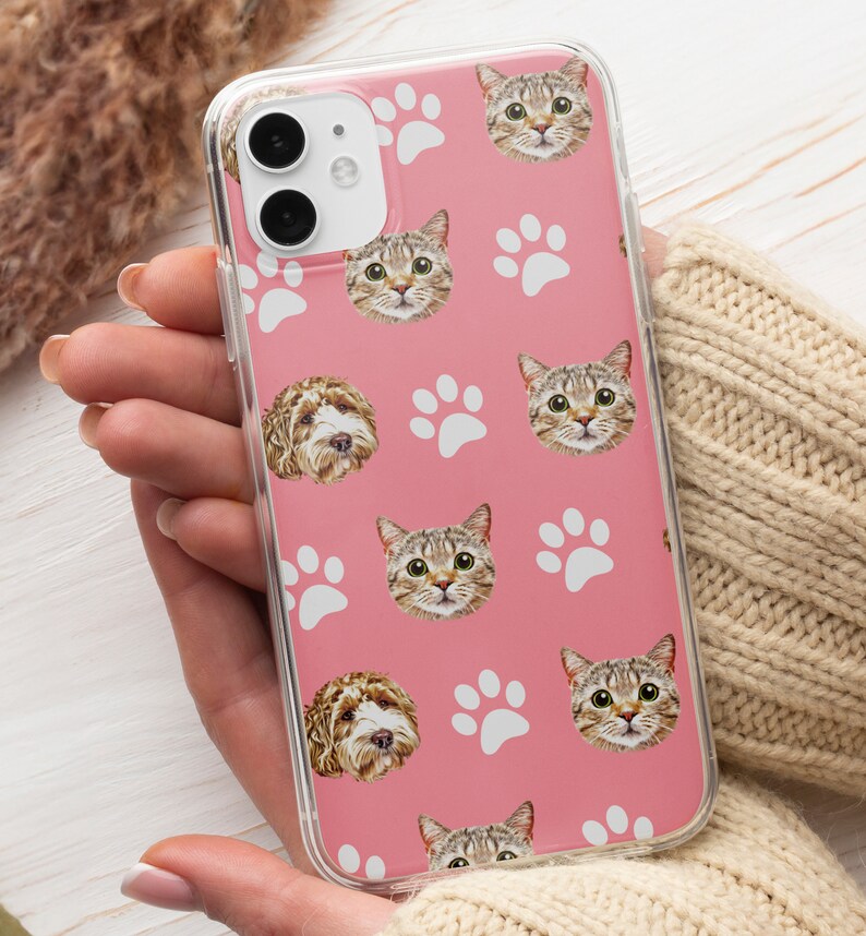 May include: A pink phone case with a repeating pattern of white paw prints and images of cats and dogs.