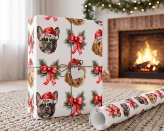 May include: White wrapping paper featuring a repeating pattern of French bulldogs and golden retrievers wearing red Santa hats, interspersed with red bows and green pine branches. Some hats are personalized with the names Max and Charlie.