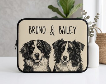 May include: A rectangular laptop sleeve with a beige background featuring a black ink-style illustration of two dogs. Above the dogs, the text BRUNO & BAILEY is printed in a simple black font. The sleeve has a black zipper and black trim.