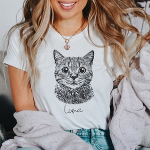 May include: White t-shirt with a black and white illustration of a cat's face and the name "Luna" printed below.