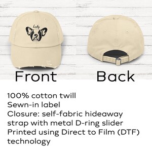 May include: A beige baseball cap with a distressed brim and a black graphic of a French bulldog face with the word Lucky printed above it. The back view shows a self-fabric strap with a metal D-ring slider for an adjustable fit and closure.