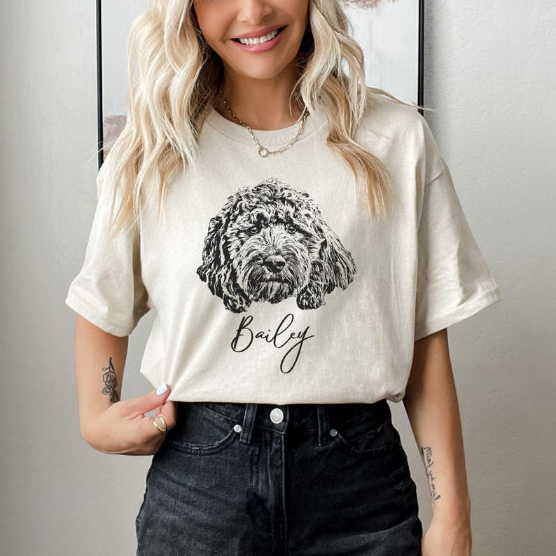 May include: A beige t-shirt with a black and white illustration of a dog and the name "Bailey" printed on the front.