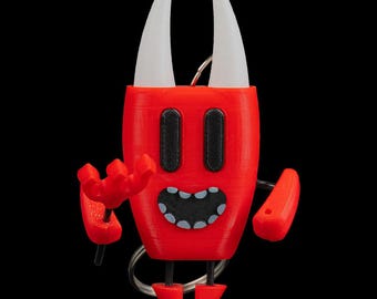 Peut inclure: Un porte-clés rouge en forme de diable avec des cornes blanches, des yeux noirs et une bouche souriante. Le porte-clés a de petits bras et jambes, et un anneau argenté. Le design est de style dessin animé, imprimé en 3D.