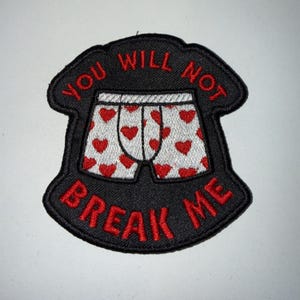 May include: A black embroidered patch featuring a white pair of boxer shorts with a red heart pattern. The text "YOU WILL NOT" is arched above the shorts in red, and the text "BREAK ME" is arched below the shorts in red, all on a black background.