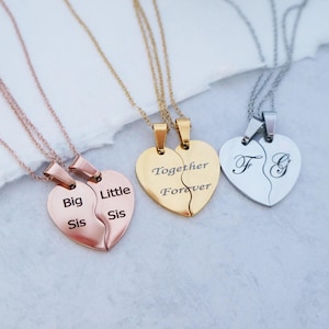 May include: Three sets of matching necklaces with heart-shaped pendants. One set features the words "Big Sis" and "Little Sis" on the pendants. Another set features the words "Together Forever" on the pendants. The third set features the letters "F" and "G" on the pendants.
