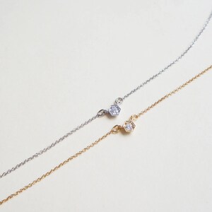 May include: Two delicate necklaces with a single diamond set in a hexagonal pendant. One necklace is silver and the other is gold.