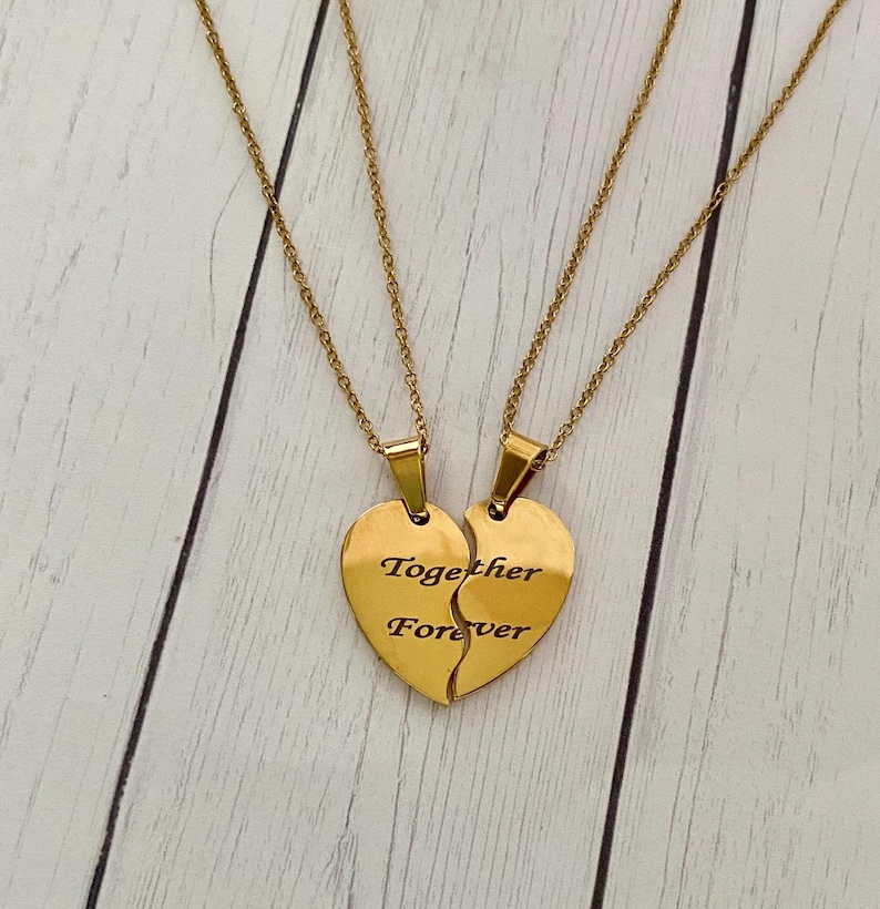 May include: Two gold necklaces with matching heart pendants that say "Together Forever" on them. The pendants are split in half, with one half saying "Together" and the other half saying "Forever".