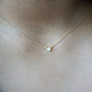 May include: A delicate gold chain necklace with a small, clear gemstone pendant.