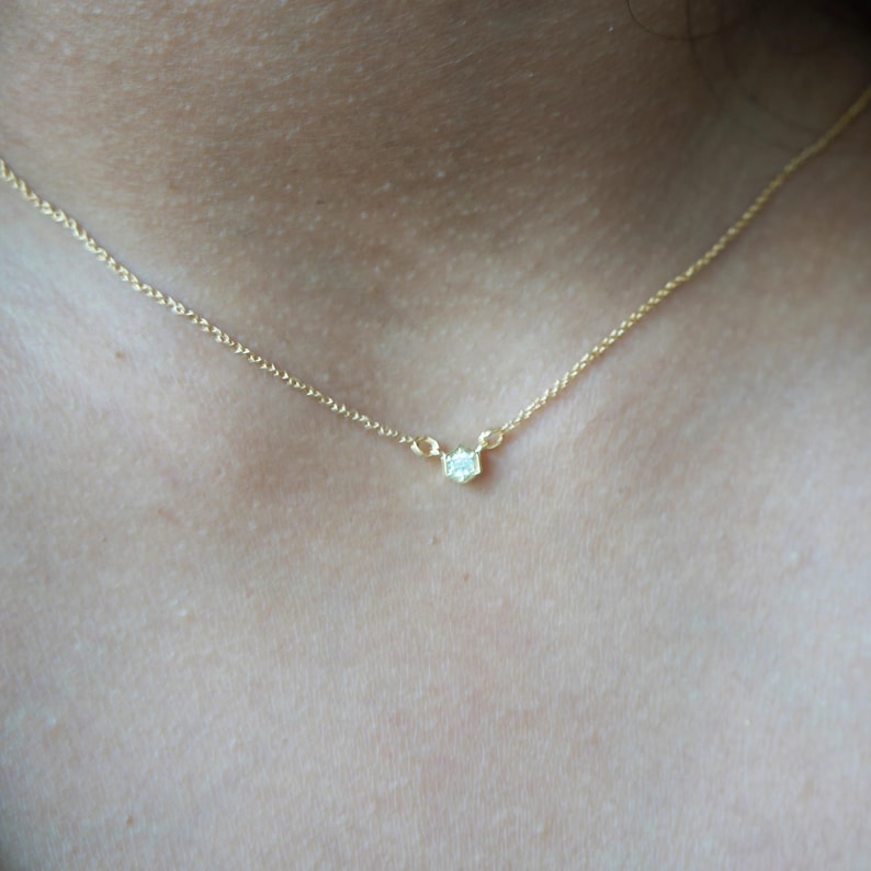 May include: A delicate gold chain necklace with a small, clear gemstone pendant.