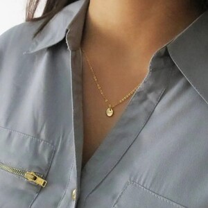 May include: A gold chain necklace with a small, round pendant. The pendant is a simple, solid circle.