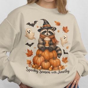 カボチャに乗ったアライグマのハロウィンスウェットシャツ | ジモシーと過ごす不気味な季節