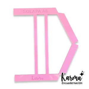 May include: Pink plastic guide for folding paper, labeled "SOLAPA A6" and "Karma Encuadernación".
