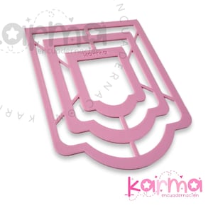May include: Three pink plastic stencils for crafting, each with a different size and shape. The largest stencil has a rounded bottom and a rectangular top with a decorative design. The stencils are labeled "Karma Encuadernacion".