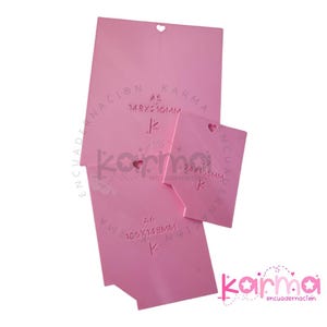 Op de afbeelding: Drie roze plastic sjablonen voor inlijsten, met hartvormige uitsnijdingen en afmetingen in millimeters. De sjablonen zijn gemarkeerd met A5, 148x210mm, A6, 105x148mm en 24x105mm. De tekst "karma encuadernacion" is afgedrukt in de rechterbenedenhoek.