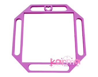 May include: A pink plastic frame with a heart cutout at the top. The frame has four handles on the sides. The frame is designed for embroidery.