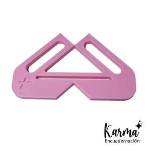 May include: Pink plastic corner tool with a star design. The tool has two slots for holding paper.