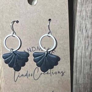 May include: A pair of black fan-shaped earrings with silver hoops. The earrings are handmade and have the text "Lindo Creations" on the card.