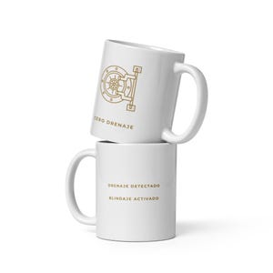 May include: Two white ceramic mugs stacked on top of each other. The top mug has a gold illustration of a vault door and the text "CERO DRENAJE". The bottom mug has the text "DRENAJE DETECTADO" and "BLINDAJE ACTIVADO" in gold.