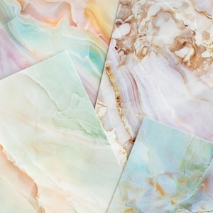 May include: A collection of five square cards with a marble-like design. The cards feature a variety of colors, including shades of yellow, orange, pink, green, and blue. The veining patterns create a natural, stone-like appearance.